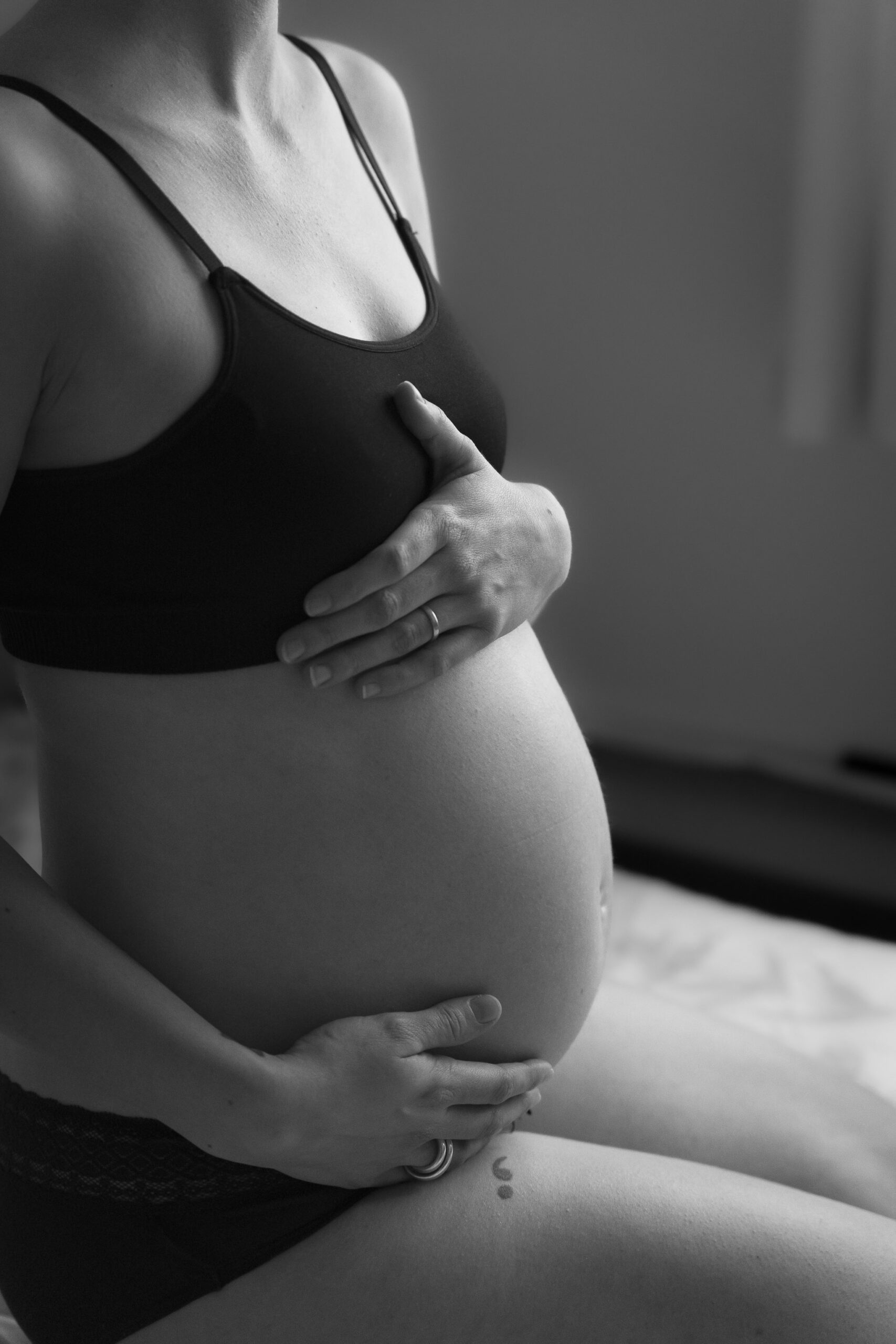 Photo noir et blanc d'une femme enceinte qui tient son ventre éclairée par la lumière naturelle à Paris