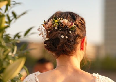 Photo de l'arrière de la mariée et de sa coiffure avec un collier de fleurs