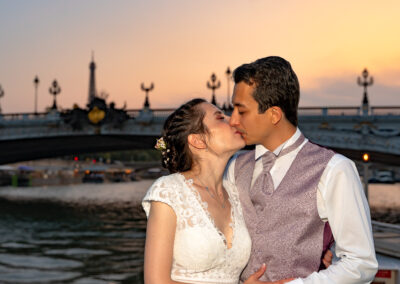 Les mariés qui s'embrassent devant le pont Alexandre III lors de leur mariage sur une péniche à Paris